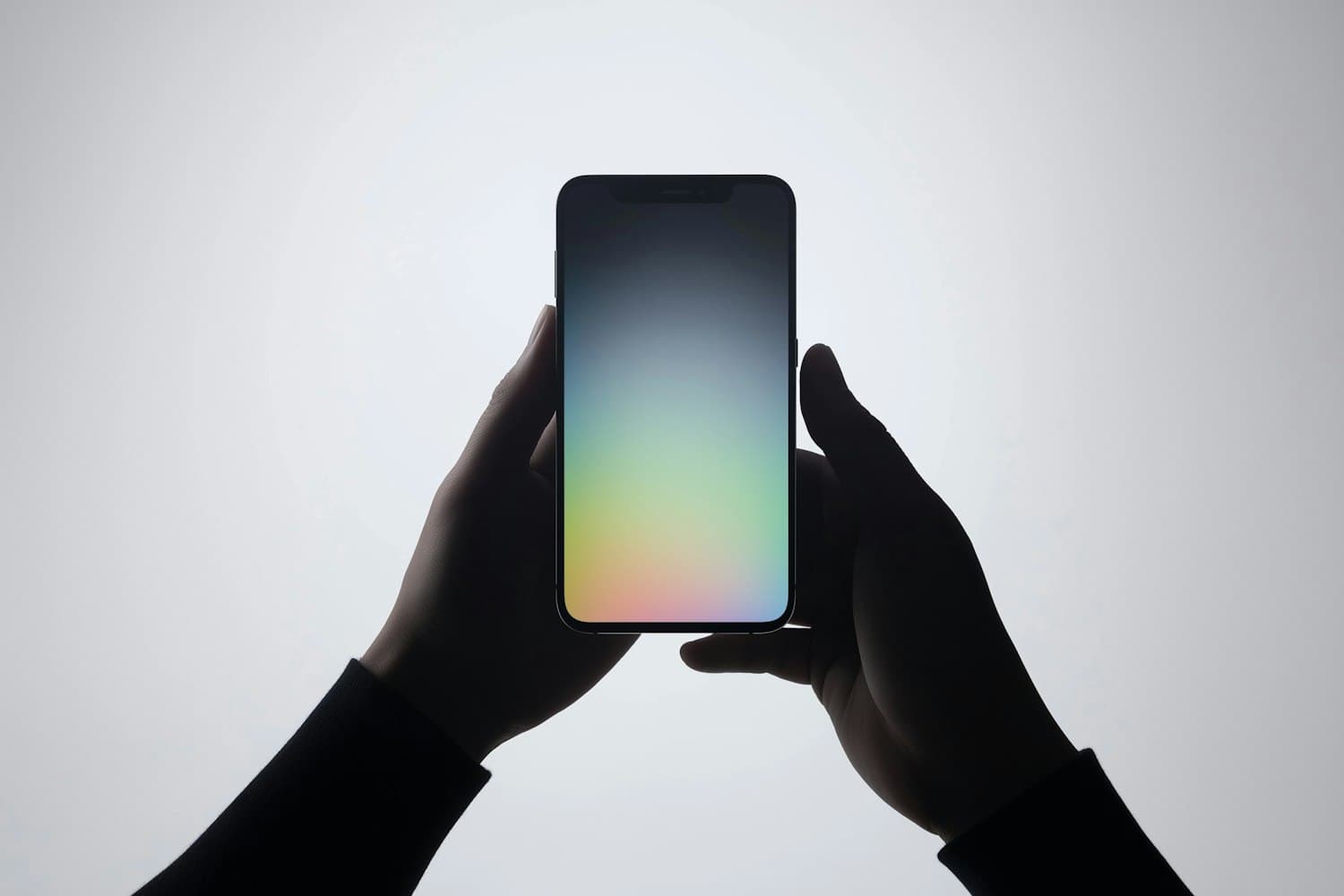 Two hands holding up a smartphone showing a soft aurora gradient on its screen